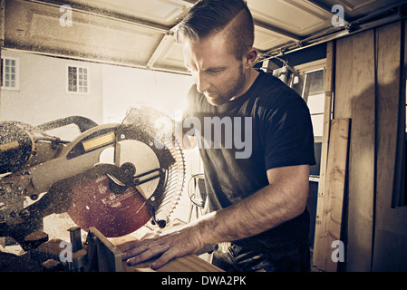 Carpintero macho aserrado tablón de madera en el taller Foto de stock