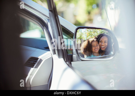 Reflejo de la sonrisa, madre e hija en retrovisor