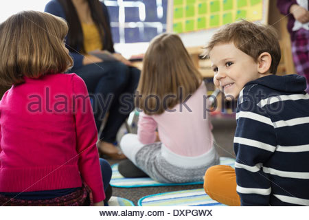 Lindo muchacho sentado en el suelo en la escuela elemental