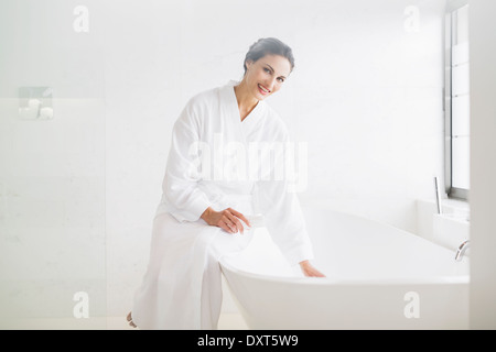 Retrato de mujer sonriente en albornoz preparando el baño Foto de stock