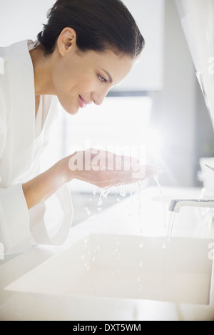 Mujer en albornoz salpicaduras de agua en la cara Foto de stock