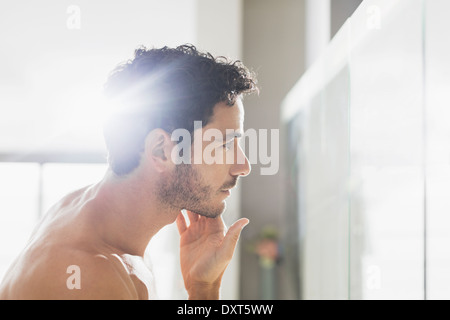 El hombre controlar la barba en el espejo del baño