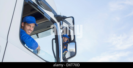 Retrato de sonriente conductor de camión asomado a la ventana Foto de stock
