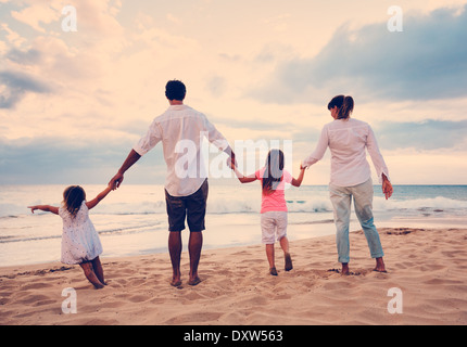 Feliz joven familia divirtiéndose en la playa en el atardecer.