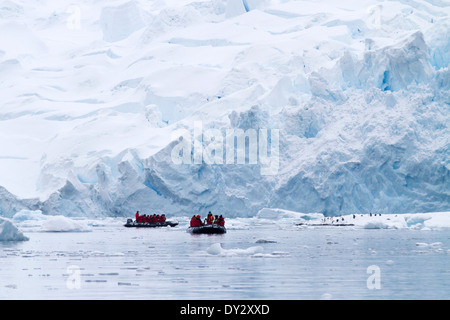 El turismo en la Antártida entre el paisaje de iceberg, glaciar, hielo y con los turistas ver pingüinos en zodiac. Península Antártica.