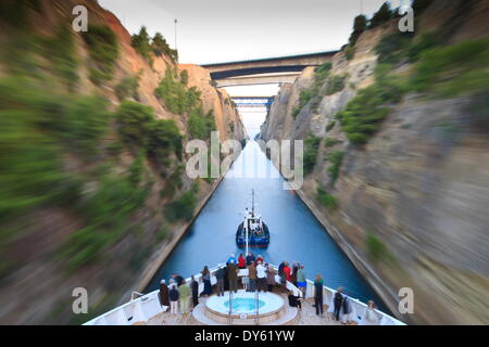 Los turistas en la proa de un crucero pequeño arrastrada por un remolcador, temprano en la mañana el tránsito del Canal de Corinto, Grecia, Europa