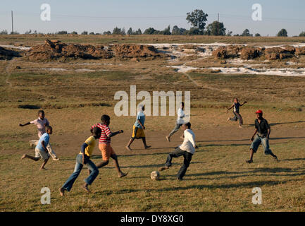 Sudáfrica, área de Witbank, 2 de septiembre de 2008: Los niños de la comunidad local, jugar a fútbol, mientras en el fondo blanco dep Foto de stock