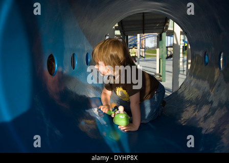 Niño de tres años jugando en el patio de recreo el túnel en el Waterfront Park de Louisville, Kentucky