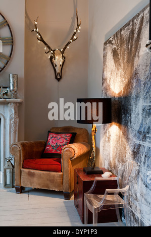 Las luces de hadas adornan una cabeza de ciervo con astas montado en pared sobre vintage sillón de piel Foto de stock