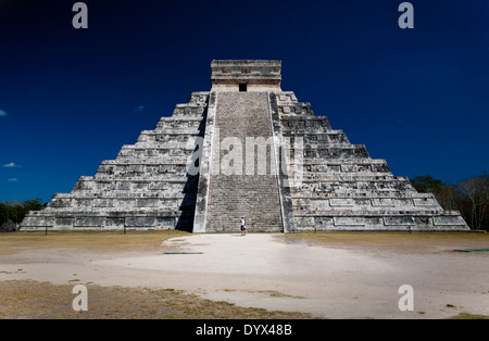 Zigurat (Pirámide) en Chichén Itzá con dos personas mirando fijamente delante de la escalera. El cielo de color azul oscuro