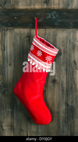 Calcetín rojo con copos de nieve para Santa regalos colgando sobre fondo de madera rústica calcetines de Navidad. Foto de stock