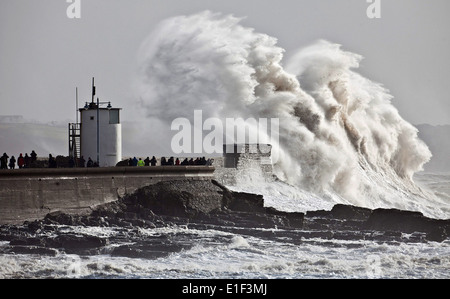 Docenas de personas paquete el malecón en Porthcawl en Gales del Sur para ver las gigantescas olas golpeando el faro Foto de stock