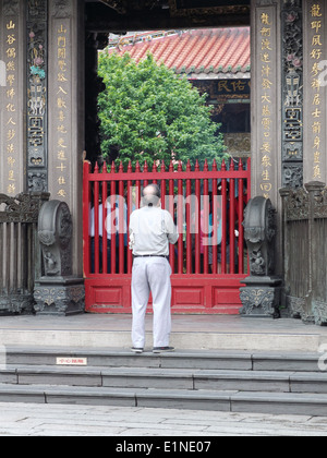 El hombre paga respecto a la puerta del templo Longshan, entre los más antiguos templos budistas de Taipei, Taiwán. Foto de stock