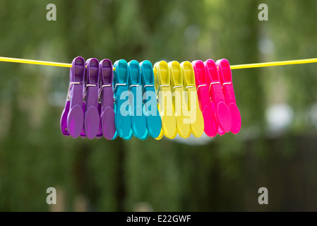 Clavijas de plástico multicolor colgando de una línea de lavado Foto de stock