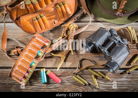 Bolsa con balas, binoculares y sombrero en un pabellón de caza Foto de stock