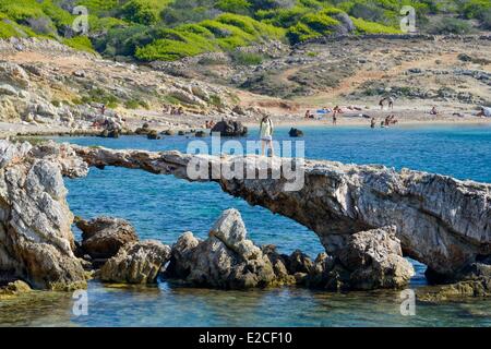 Italia, Sicilia, las islas Egadi, la isla de Favignana, Cala Rotonda, joven caminando sobre el puente natural excavado por el mar en las rocas Foto de stock