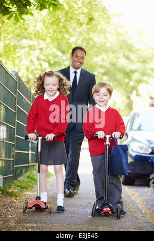 Los niños con motocicletas en su camino a la escuela con el Padre Foto de stock