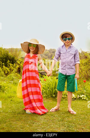 Chico y chica luciendo sombrero de paja y gafas de sol sonriente