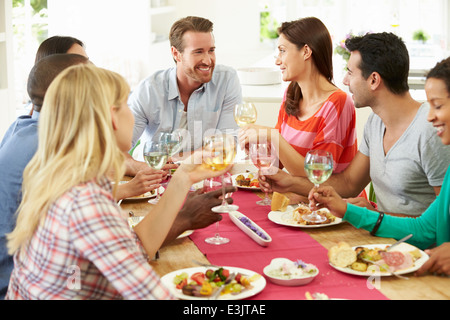 Grupo de Amigos hacer tostadas en torno a una mesa en la Cena Foto de stock