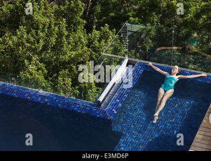 Mujer flotando en la piscina de lujo