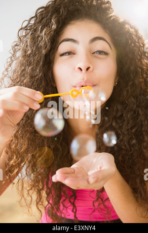 Mujer de raza mixta soplando burbujas