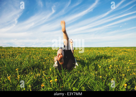 Mujer joven tumbado en la hierba con piernas levantadas Foto de stock