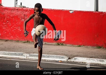 (140701) -- El Salvador, 1 de julio de 2014 (Xinhua) -- Un niño juega al fútbol en una calle en Salvador, Brasil, el 1 de julio de 2014. (Xinhua /Jhon Paz)(pcy) Foto de stock