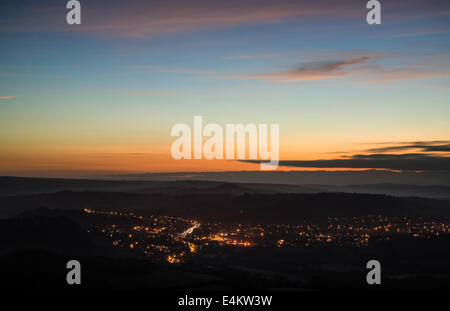 Hermoso paisaje antes del amanecer con vistas a las luces de la ciudad en el valle Foto de stock