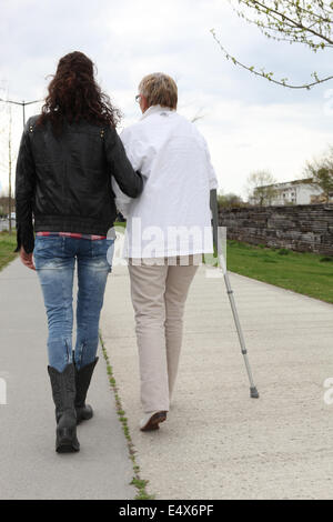 Mujer joven ayudando anciana caminar Foto de stock