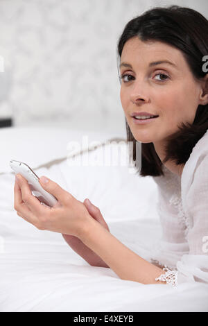 Mujer sentado en una cama enviar mensaje de texto Foto de stock