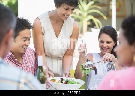 Mujer sirviendo a los amigos en la mesa al aire libre
