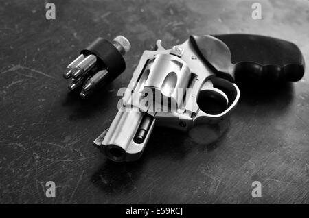 Primer plano de una potente pistola con balas sobre superficie de madera vieja Foto de stock