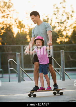 El padre y la hija de equitación en skate park