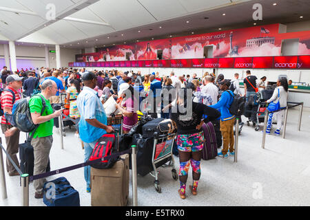 Larga cola de pasajeros que esperan para facturar en Virgin Atlantic escritorios. Foto de stock