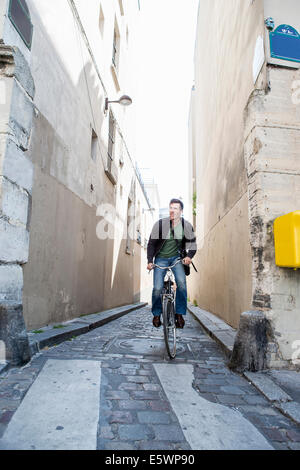 Mitad hombre adulto ciclismo sobre guijarros angosta calle, París, Francia