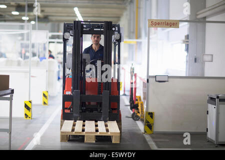Hombre maduro con carretilla elevadora en la fábrica. Foto de stock