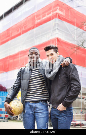 Retrato de dos jóvenes en la calle sosteniendo un balón de fútbol
