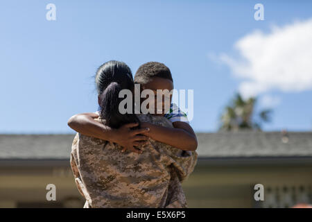 Vista trasera de la mujer soldado abrazando a hijo en casa Foto de stock
