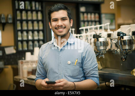 Retrato de barista con el smartphone en cafe Foto de stock