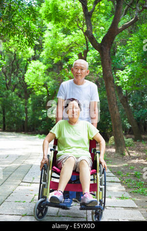 Senior mujer sentada en una silla de ruedas con su marido