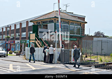 Los peatones en el cruce del ferrocarril y la señal de verificación en Polegate Sussex. UK
