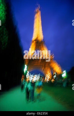 Vista trasera de parejas caminando hacia la Torre Eiffel por la noche Foto de stock