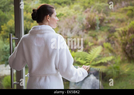 Mujer vistiendo albornoz contra plantas borrosa Foto de stock