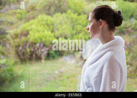 Mujer vistiendo albornoz contra plantas borrosa Foto de stock