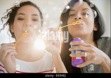 Madre e hija soplando burbujas juntos