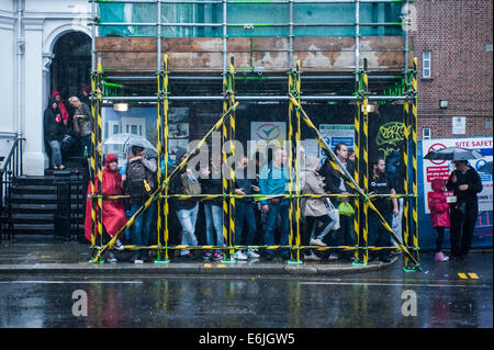 Londres, Reino Unido. 25 Aug, 2014. La gente protegerse de fuertes lluvias durante el carnaval de Notting Hill en Londres. Crédito: Piero Cruciatti/Alamy Live News Foto de stock