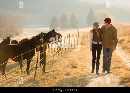 Pareja joven caminando en la granja de caballos