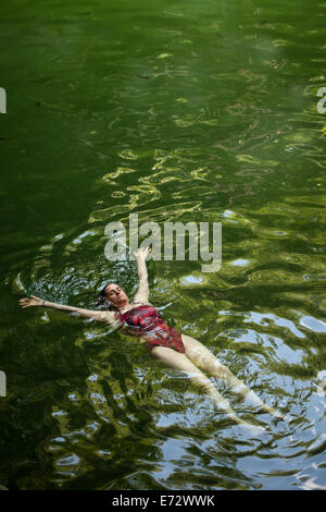 Una mujer nadando en el Cenote Xcanche cerca de la ciudad maya de Ek Balam, Península de Yucatán, México, 10 de agosto de 2014. Foto de stock