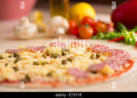 Materias salami pizza en la mesa con los ingredientes Foto de stock