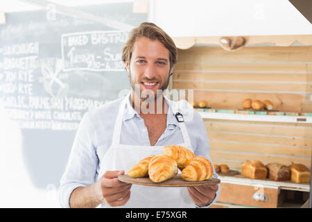 Guapo mozo sosteniendo una bandeja de croissants Foto de stock